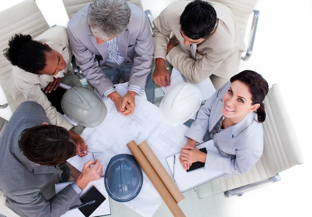 High angle of multi-ethnic architects studying blueprints