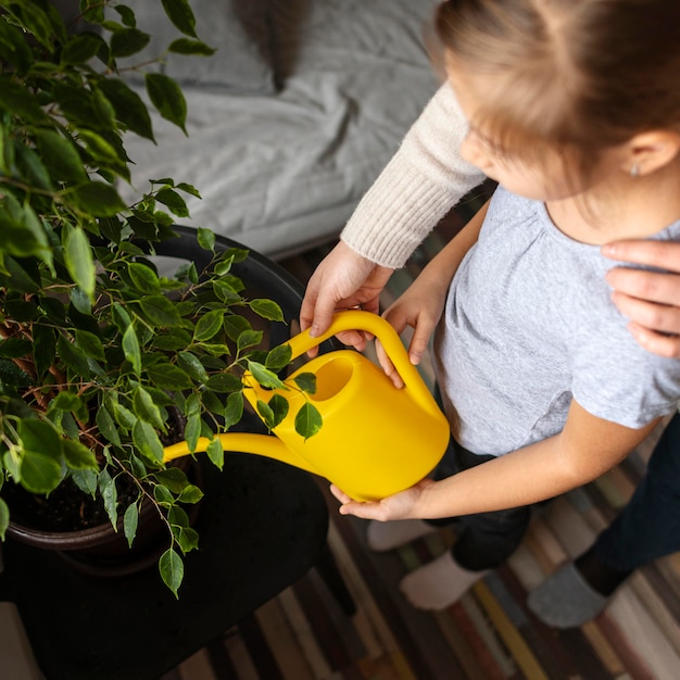 写真 自宅で植物に水をまく少女の高角度