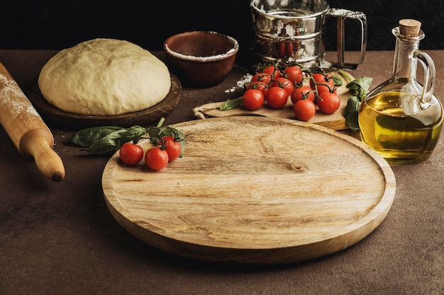 Foto alto angolo di pasta per pizza con tavola di legno e pomodori