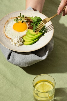 Angolo alto del piatto con cibo dietetico cheto e un bicchiere d'acqua con limone