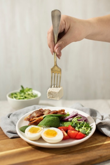 Photo high angle of plate with keto diet food and a hand holding a fork