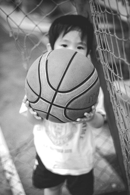 Photo high angle portrait of boy holding ball while standing by net