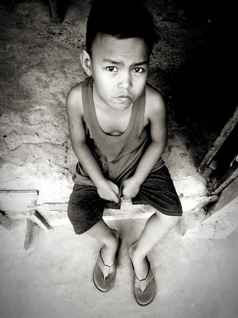 Photo high angle portrait of boy sitting outdoors