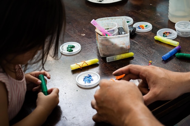 Photo high angle portrait of family painting togeher using glitter glue arts and craft set