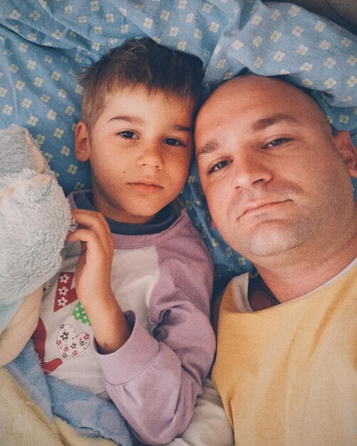 Foto ritratto ad alto angolo di padre e figlio sdraiati a letto a casa