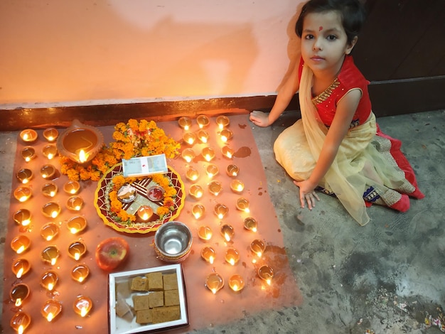 high angle portrait of girl sitting by lit diyas on floor