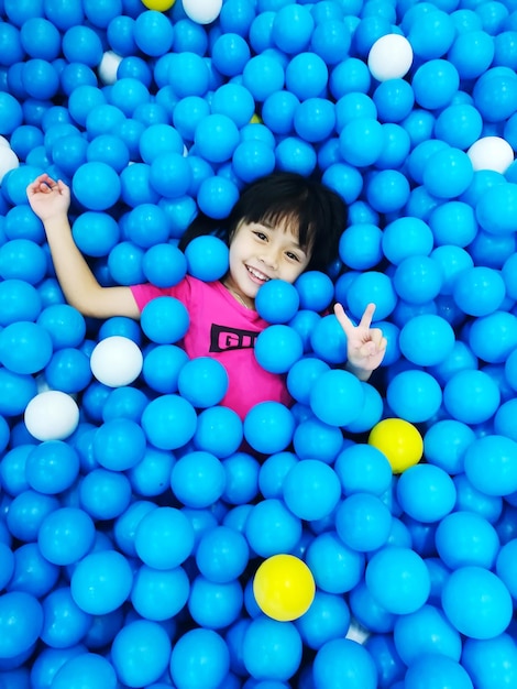 Foto ritratto ad alto angolo di una ragazza che sorride mentre giace in una piscina da palla