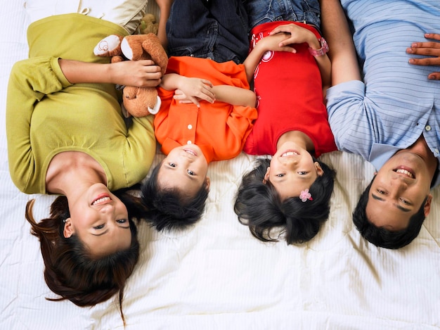 high angle portrait of happy family lying on mattress at home