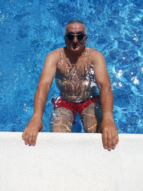 High angle portrait of mature man in swimming pool during summer