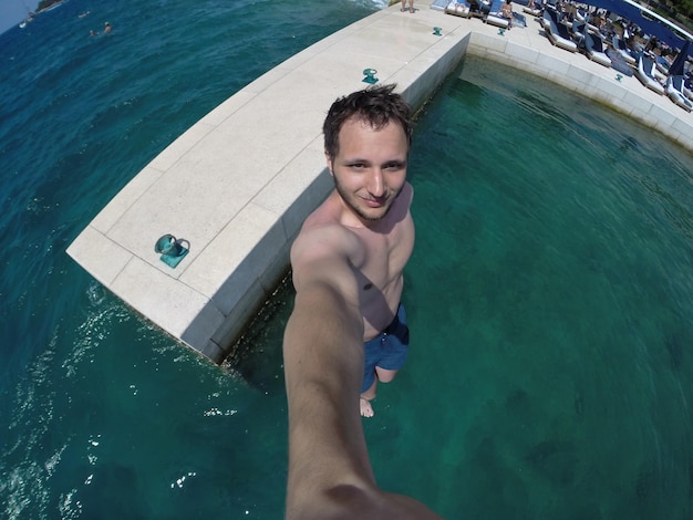 High angle portrait of shirtless man standing in river during sunny day