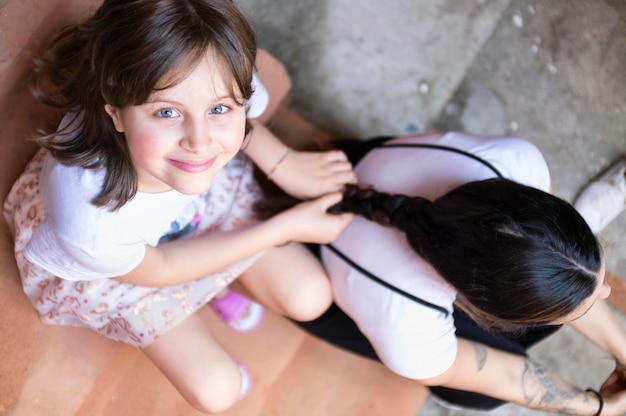 High angle portrait of smiling girl tying mother hair