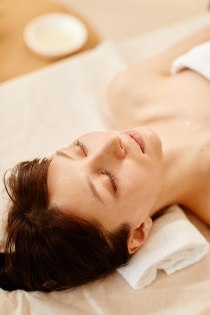 High angle portrait of smiling young woman enjoying relaxing spa session in health club copy space