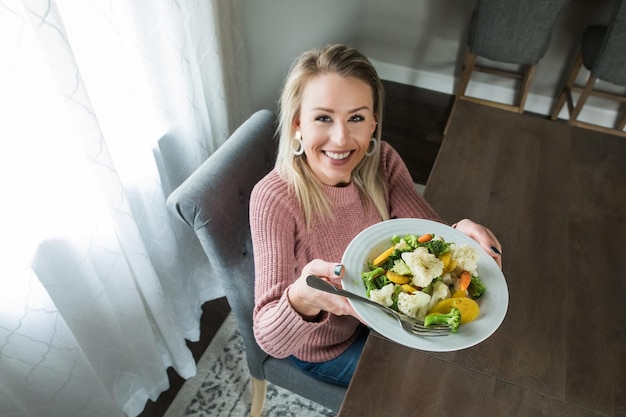 Photo high angle portrait of smiling young woman holding food while sitting at table