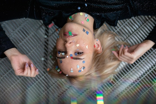 Photo high angle portrait of woman with confetti on face lying on floor