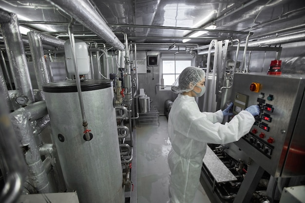 High angle portrait of young female worker operating machine units at clean food production factory, copy space