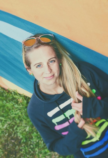 High angle portrait of young woman smiling by wall