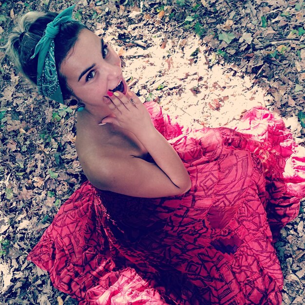 High angle portrait of young woman wearing red dress on field