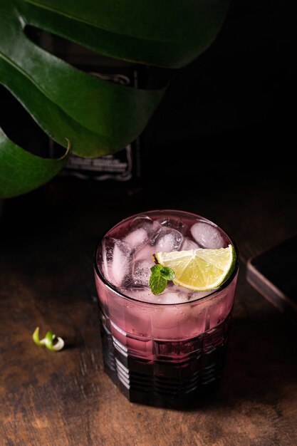 High angle of purple glass with iced cocktail with lime