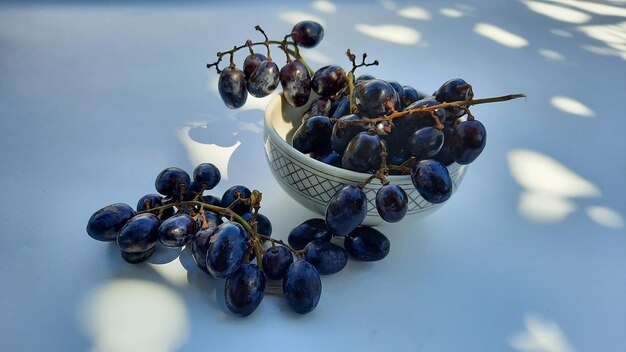 Angolo alto, uva viola in una ciotola con gambo isolato su sfondo bianco e ombra 04