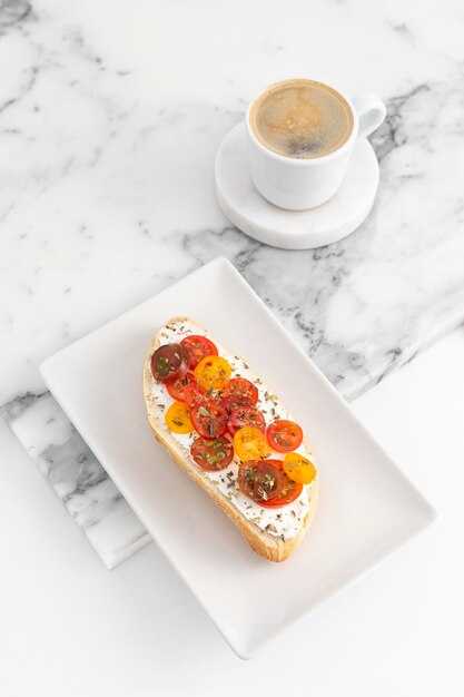 High angle sandwich with cream cheese and tomatoes on plate with coffee