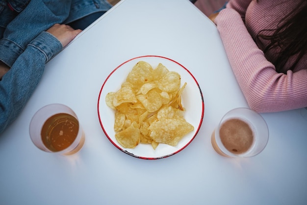 사진 바 테라스에서 칩과 맥주잔 두 잔으로 가득 찬 접시의 높은 각도 샷