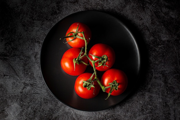 Высокий угол снимка красных помидоров на синей тарелке
