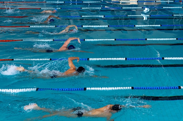 写真 スイミングプールでの男性水泳選手の多民族グループの高い角度の側面図、レーンで競い合い、クロールを泳ぐ