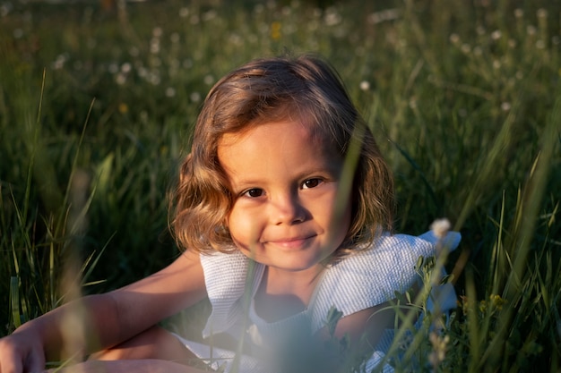 Foto ragazza sorridente di alto angolo che si siede sull'erba