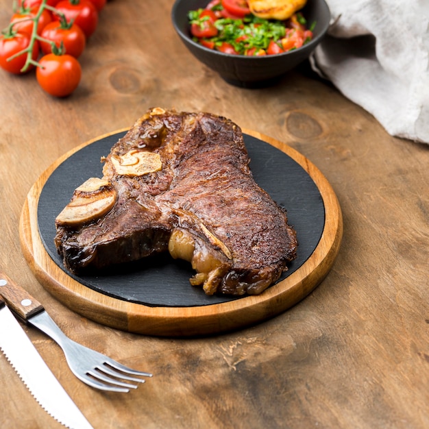 Photo high angle of steak with cutlery and tomatoes