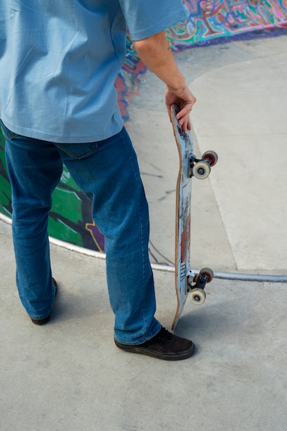 Skateboard teenager della tenuta dell'angolo alto