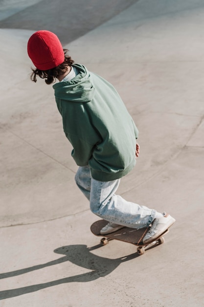 Photo high angle of teenager with skateboard having fun