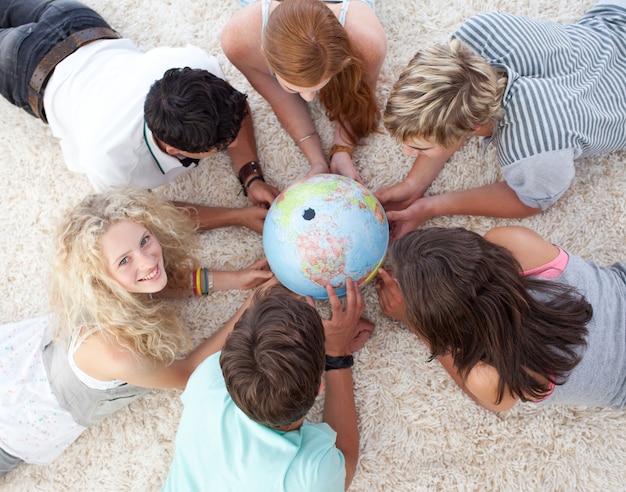 Foto alto angolo di adolescenti sul pavimento esaminando un mondo terrestre