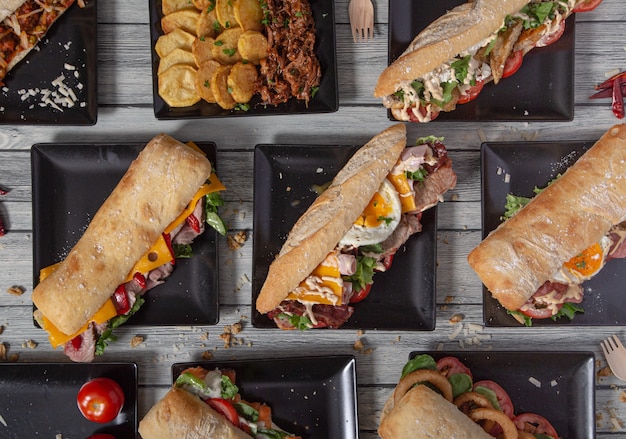 high angle of a variety of delicious sandwiches with a variety of ingredients on a wooden table.
