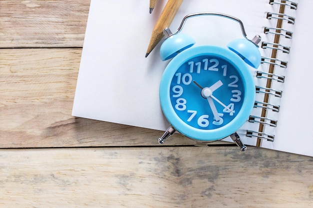 Foto vista ad alto angolo di orologio sveglia e penna su sfondo di tavolo in legno nel posto di lavoro dell'ufficio