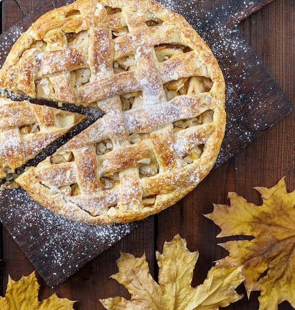 Высокоугольный вид яблочного пирога на доске для резки осенними листьями