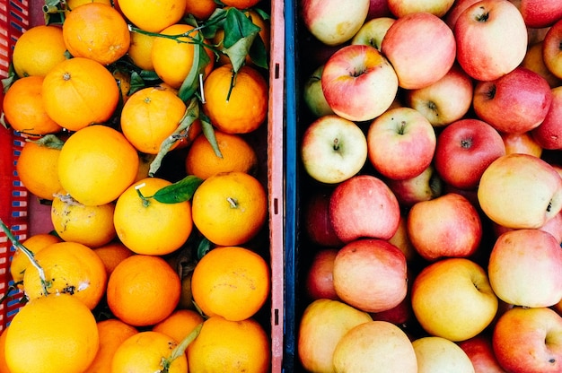 Photo high angle view of apples and oranges in container at market for sale