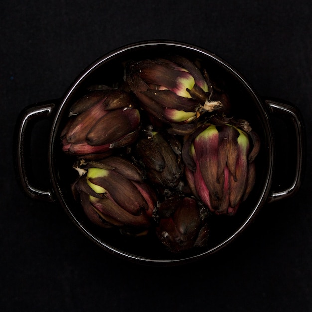 Photo high angle view of artichoke in container over black background