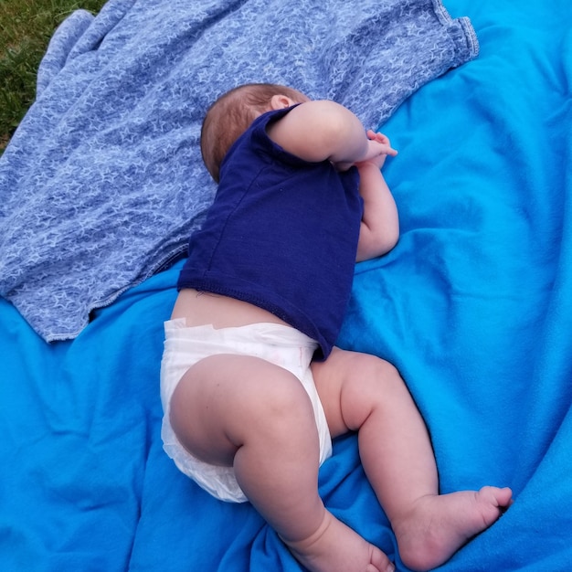 High angle view of baby boy lying on blue sheet