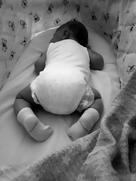 High angle view of baby boy sleeping on crib at home