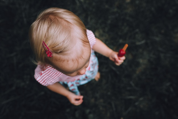 Photo high angle view of baby girl holding flavored ice cream