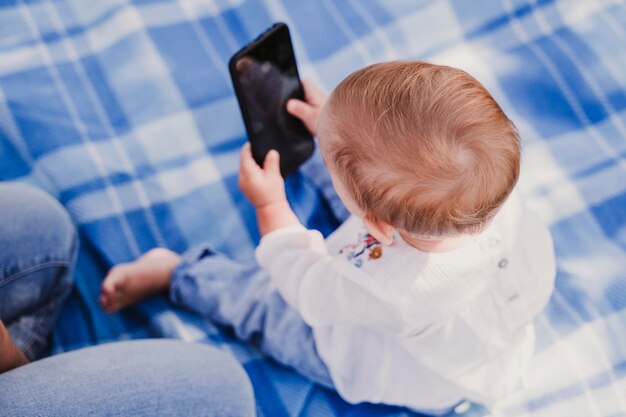 Photo high angle view of baby girl using mobile phone at home