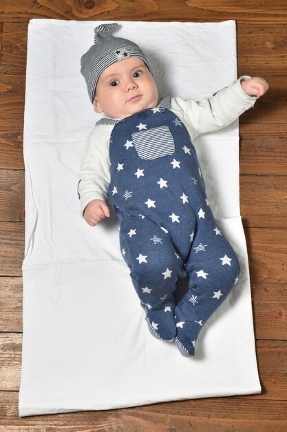 High angle view of a baby on the parquet floor in dressed and cap