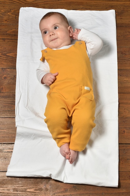 High angle view of a baby on the parquet floor dressed,