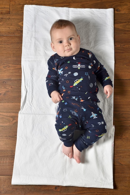 High angle view of a baby on the parquet floor in pajamas,looking at camera