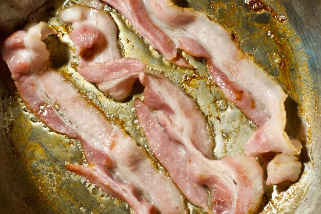 Photo high angle view of bacon frying in saucepan