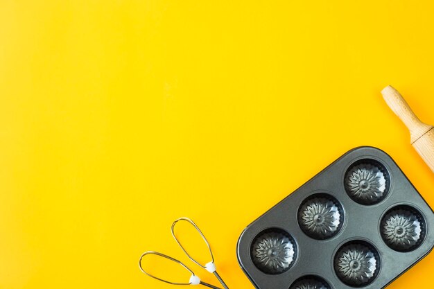 High angle view of baking sheet with rolling pin on yellow background