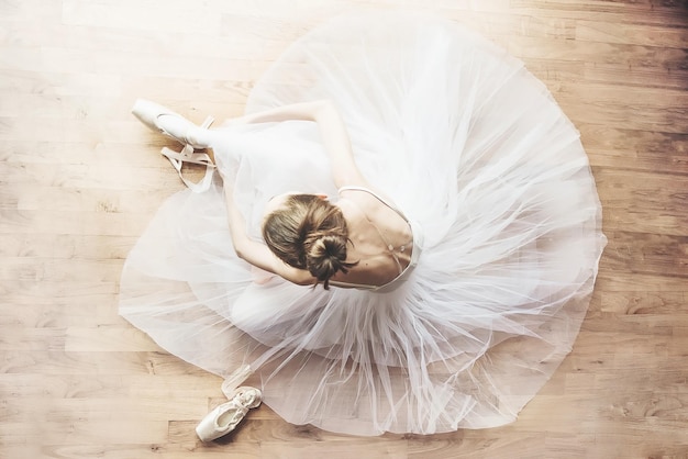 Foto vista ad alto angolo della ballerina seduta sul pavimento di legno duro