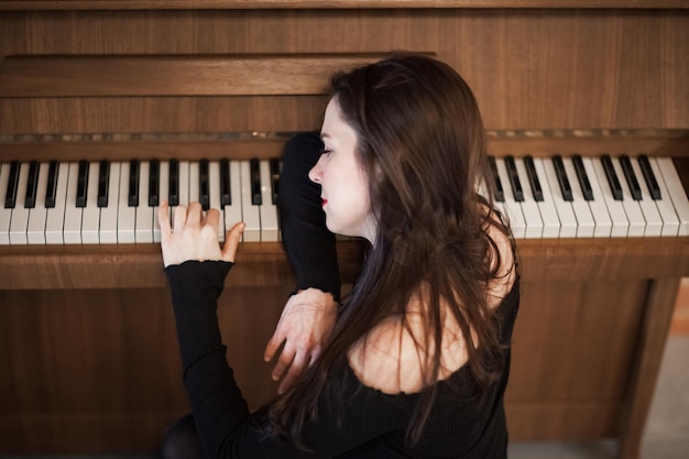 집에 앉아 피아노를 연주하는 아름다운 여성의 높은 각도 시각