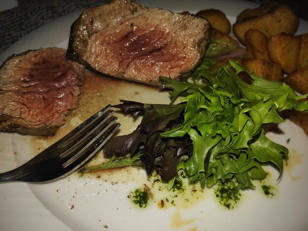 Foto vista ad alta angolazione di bistecca di manzo e patate servite da insalata in piatto