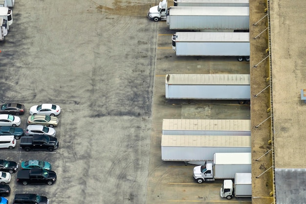 많은 화물 트럭이 추가 유통을 위해 상품을 내리고 업로드하는 대형 상업 물류 센터의 높은 각도 보기 글로벌 경제 개념
